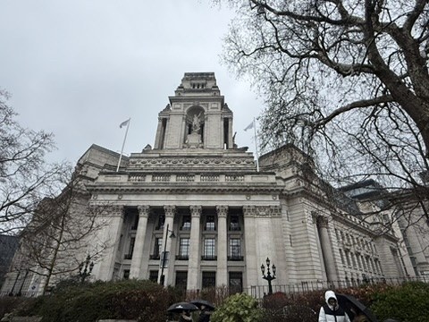 A stone civic building with columns beneath a cloudy sky.